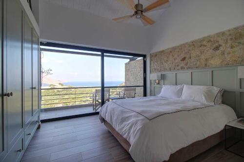 a bedroom with a large bed and a large window at Villa Simera, with pool & great view in Fournádhos