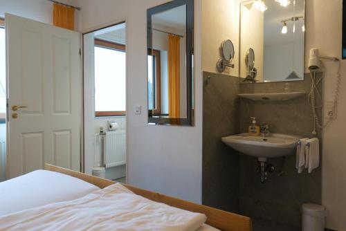 a bathroom with a sink and a bed and a mirror at Weinhaus am Schieferfels in Veldenz