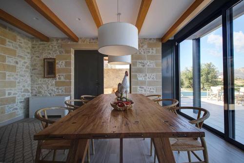a dining room with a wooden table and chairs at Villa Simera, with pool & great view in Fournádhos