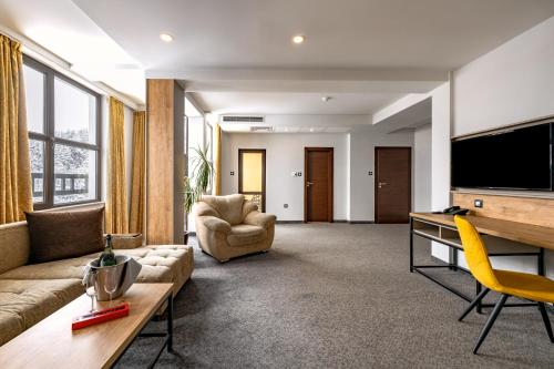 a living room with a couch and chairs and a tv at Grand Hotel Velingrad in Velingrad