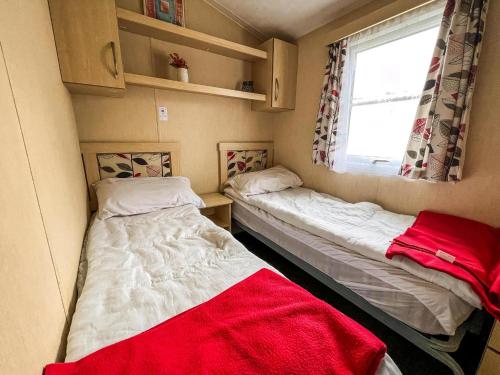 zwei Betten in einem kleinen Zimmer mit Fenster in der Unterkunft Dog Friendly 8 Berth Caravan At Dovercourt Holiday Park In Essex Ref 44504P in Great Oakley