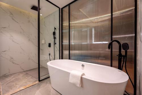 a white bath tub in a bathroom with a shower at Radisson Resort Khopoli in Khopoli