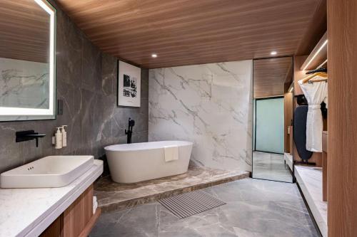 a bathroom with a white tub and a sink at Radisson Resort Khopoli in Khopoli