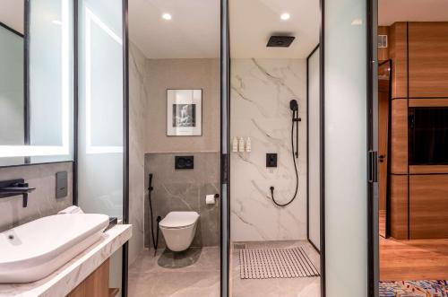 a bathroom with a shower and a toilet and a sink at Radisson Resort Khopoli in Khopoli