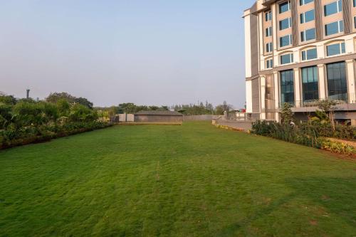 a large field of grass next to a building at Radisson Resort Khopoli in Khopoli