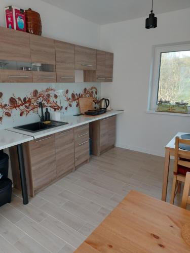 a kitchen with wooden cabinets and a sink and a table at Dom Nad Potokiem Średnia Wieś in Hoczew