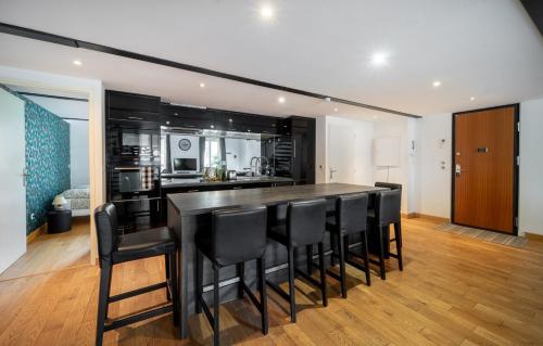 une cuisine avec un bar et des tabourets de bar noirs dans l'établissement Loft - Climatisation, Parking, Tout équipé, à Montpellier