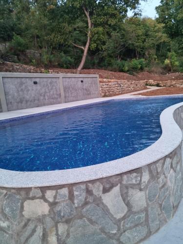 a swimming pool with a stone wall around it at Serbina in Kandalica