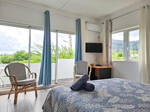 a bedroom with a bed and two chairs and a television at Studio Indian by IHR in La Gaulette