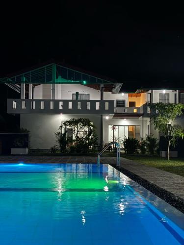 a swimming pool in front of a house at night at LiliVilla Srilanka in Aluthgama