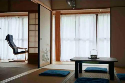a room with a table and a chair and windows at Rebe東吉野 in Washika