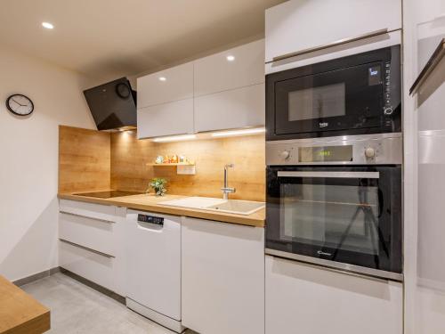 une cuisine avec des armoires blanches et un micro-ondes dans l'établissement Apartment L'Atalante by Interhome, à Sainte-Maxime
