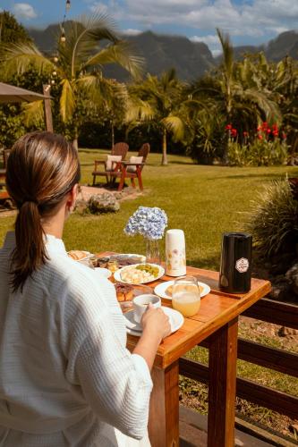 a woman sitting at a table with food on it at Cabanas Jardim dos Canyons in Praia Grande