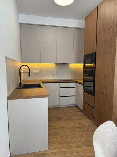 eine Küche mit weißen Schränken und einer Spüle in der Unterkunft Apart Hotel Spa Resort Becici, Budva Апартаменты с двумя мастер-спальнями in Becici