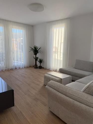 ein Wohnzimmer mit Couch, Tischen und Fenstern in der Unterkunft Apart Hotel Spa Resort Becici, Budva Апартаменты с двумя мастер-спальнями in Becici