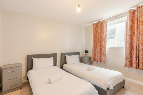 two twin beds in a room with a window at Hummingbird House in Cockermouth