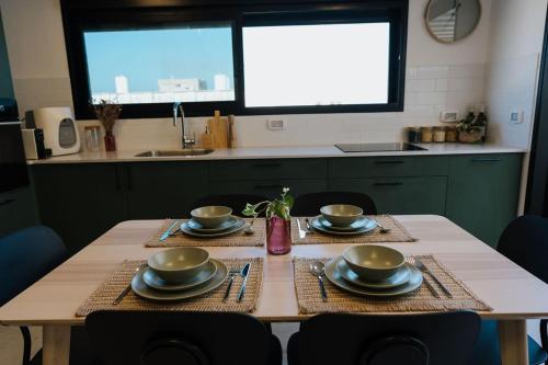 a kitchen table with plates and utensils on it at Communit Penthhous - Urban Vacation & Port View in Haifa
