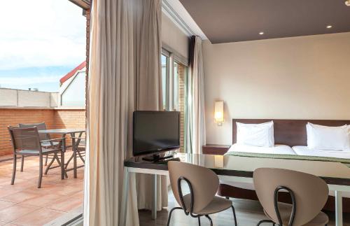 a hotel room with a bed and a desk with chairs at Suites Viena Plaza de España in Madrid