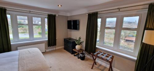 a bedroom with windows and a bed and a chair at #4 - King Room at The Raven Aparthotel by PureStay in Much Wenlock