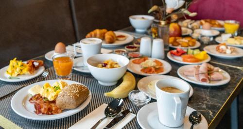 a table with plates of food and cups of coffee at PLAZA Premium Parkhotel Neu-Ulm in Ulm