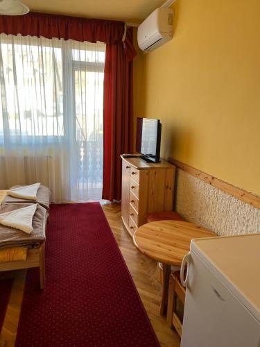 a small room with a table and a bench and a kitchen at Gyógygödör Vendégház in Szekszárd