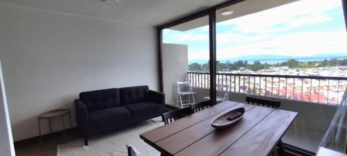 a living room with a couch and a wooden table at Hermoso Dpto con vista Lago y Volcanes in Llanquihue