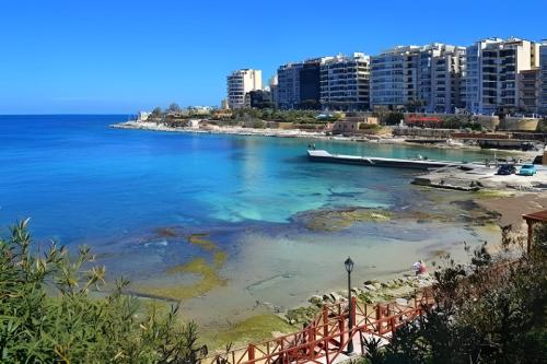 a view of a beach with a boat in the water at Kirxa Rooms and Suites in Sliema