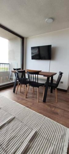 a dining room with a table and chairs and a television at Hermoso Dpto con vista Lago y Volcanes in Llanquihue