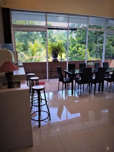 a dining room with tables and chairs and a large window at Ubud Suites Batuan in Sukawati