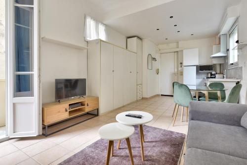 un salon avec un canapé, une télévision et une table dans l'établissement Vieux Nice Studio avec balcon à 1min de la plage, à Nice