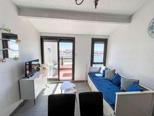un salon avec un canapé bleu devant une fenêtre dans l'établissement Apartment Palmyra-7 by Interhome, au Barcarès