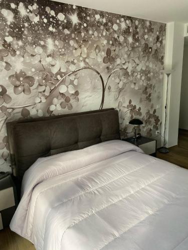 sypialnia z białym łóżkiem i kwiatową ścianą w obiekcie Cassino - Appartamento Grey - Parco del Gari w mieście Cassino