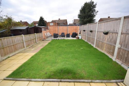 a garden with a fence and green grass at Bright and Cosy Studio Apartment by Jesswood Properties Short Lets With Free Parking Near M1 & Luton Airport in Luton