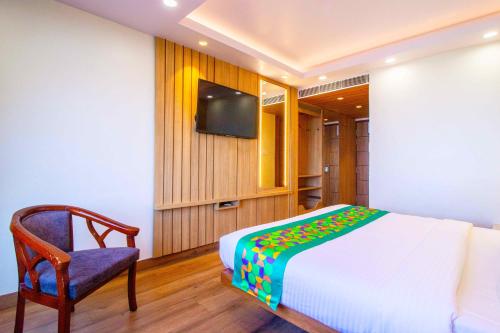 a bedroom with a bed and a chair and a television at Treebo Varuna With Mountain View in Shimla
