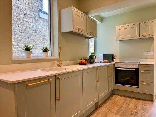 a kitchen with white cabinets and a sink at Stunning 4-Bedroom Home - 10 mins to Sandbanks Beach in Poole