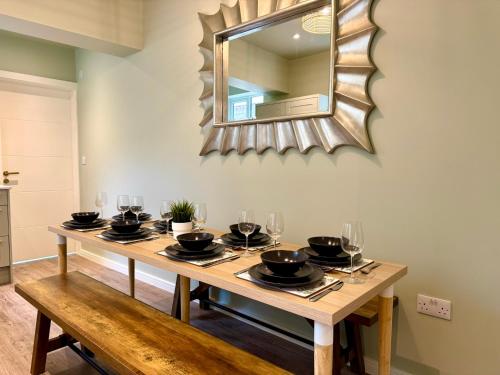 a dining room table with a mirror on the wall at Stunning 4-Bedroom Home - 10 mins to Sandbanks Beach in Poole