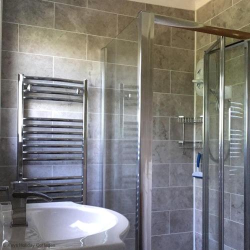 a bathroom with a shower and a tub and a sink at 35 Siesta Mar in Mundesley