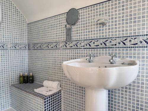 a blue tiled bathroom with a sink and a mirror at Stargazers Cottage in Doolin