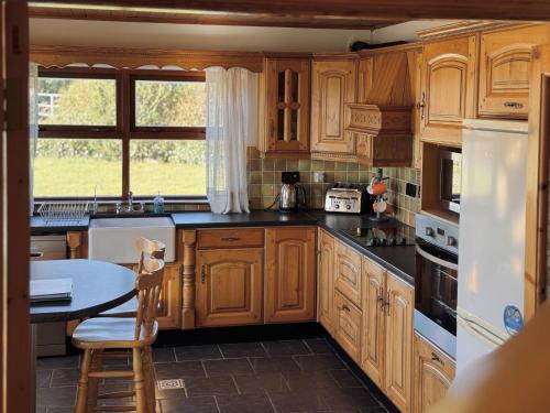 a kitchen with wooden cabinets and a table in it at Stargazers Cottage in Doolin