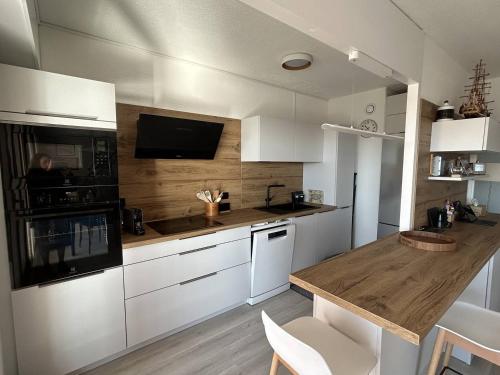 une cuisine avec des armoires blanches et un comptoir en bois dans l'établissement Magnifique Appartement T3 4 pers vue panoramique port et mer HYE200-230, à Hyères