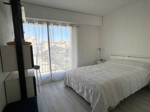 une chambre blanche avec un lit et une grande fenêtre dans l'établissement Magnifique Appartement T3 4 pers vue panoramique port et mer HYE200-230, à Hyères