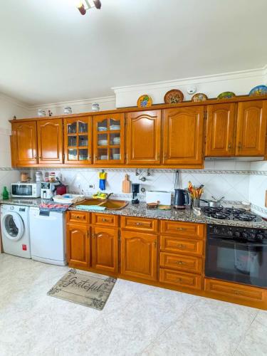 a kitchen with wooden cabinets and a white dishwasher at Superhost Stay Garden View Double Room near Lisbon and Beaches in Corroios