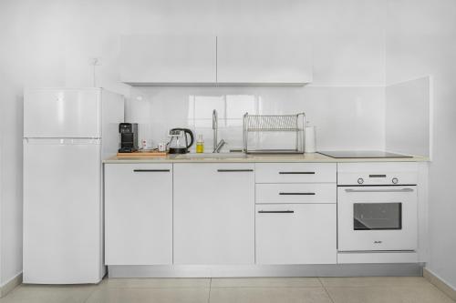 a white kitchen with white cabinets and appliances at Luxury Suite Apartment #67 By Hashdera Eilat in Eilat