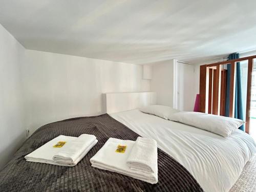 a white bed with two towels on top of it at Libergier superbe T2 à côté de la cathédrale in Reims
