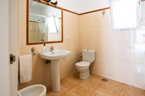 een badkamer met een wastafel, een toilet en een spiegel bij A&N Refugio del Mar in Torre del Mar