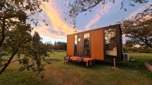 a small house with a bench and a table at Applewood Cabin 1 by Tiny Away in Christchurch