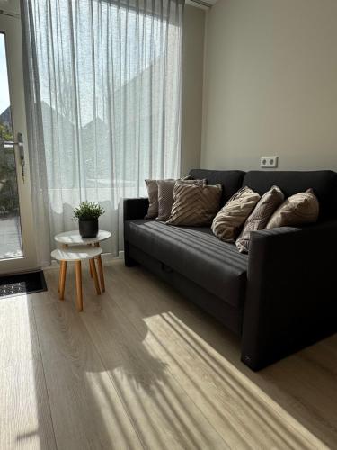 a black couch in a living room with a window at Logies het Noordwestertje in Den Burg