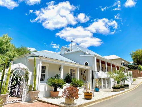 a white house with potted plants on a street at 1 Royal Street Guesthouse in Riebeek-Kasteel