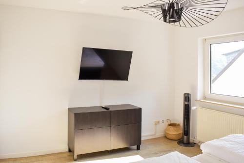 a bedroom with a dresser with a tv on the wall at Hotel Emmerich in Winningen