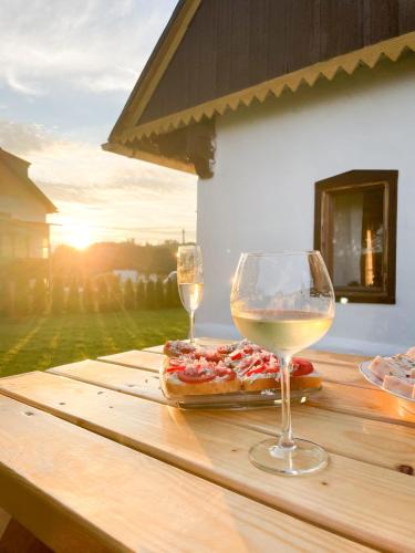 two glasses of wine sitting on a wooden table with a pizza at Chalupa Rozálka in Cerny Dul